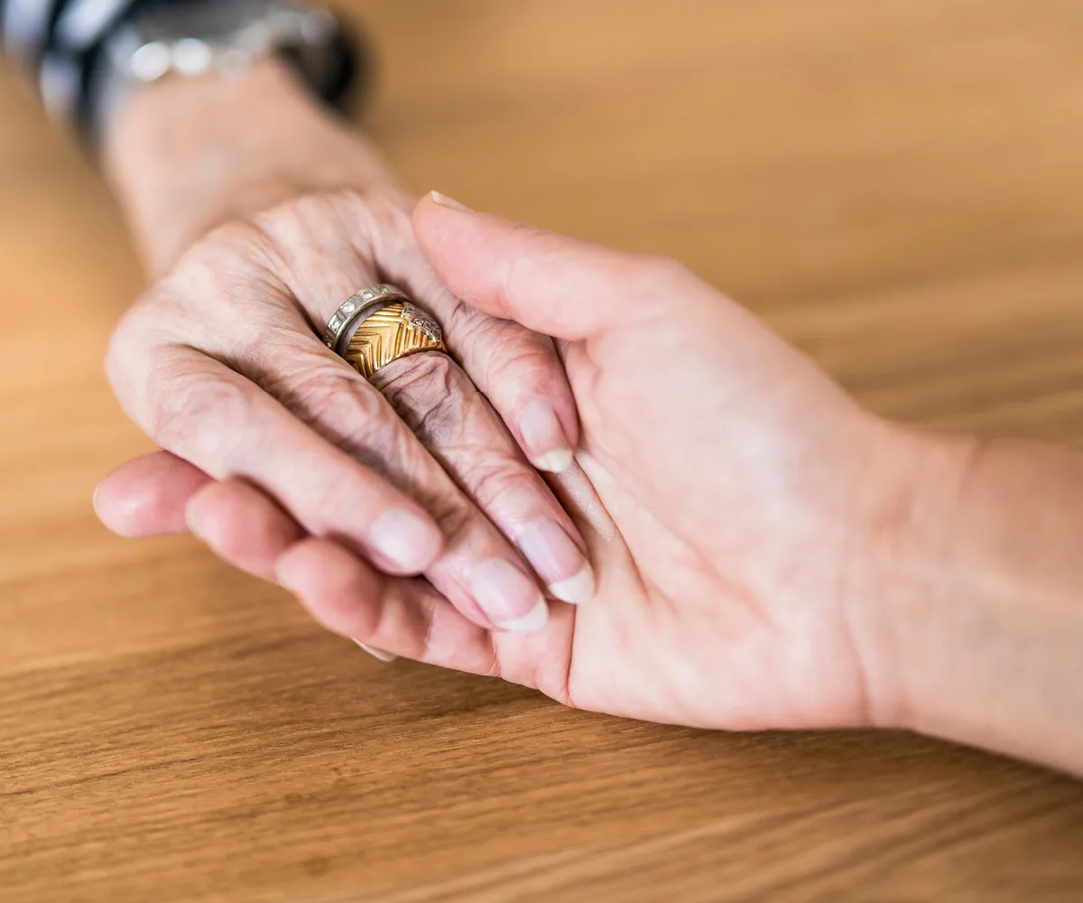 Junge Hand hält ältere Hand mit Ringen